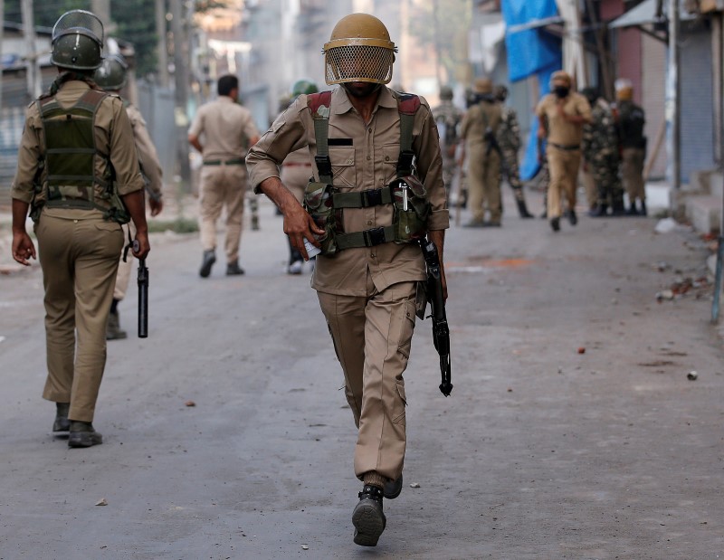 © Reuters. An Indian policeman runs during a protest in Srinagar against the recent killings in Kashmir