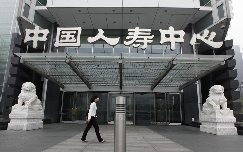 © Reuters. A woman walks past China Life Insurance Co Ltd headquarters building at Beijing's Financial Street