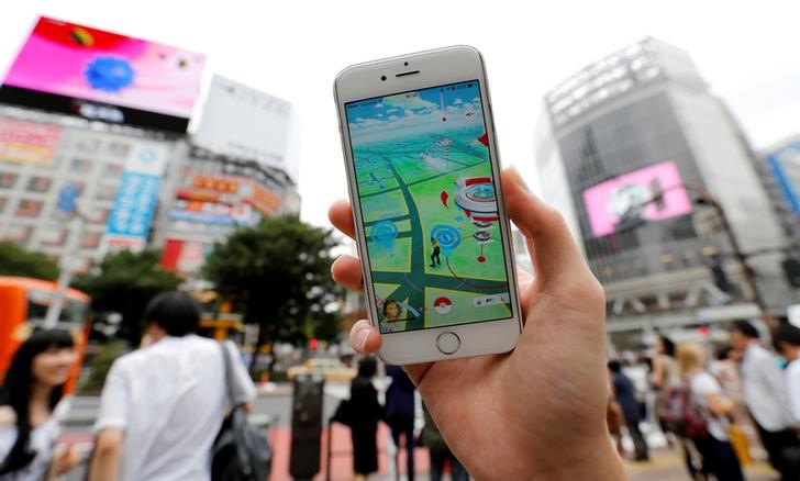 © Reuters. Homem posa com seu celular mostrando o jogo de realidade aumentada Pokémon Go em um cruzamento movimento no distrito de Shibuya, em Tóquio, no Japão