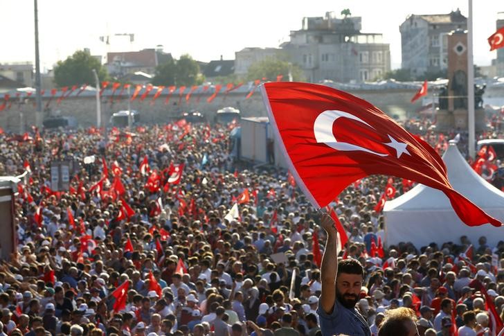 © Reuters. A man waves Turkey's national flag as he with supporters of various political parties gathers in Istanbul's Taksim Square