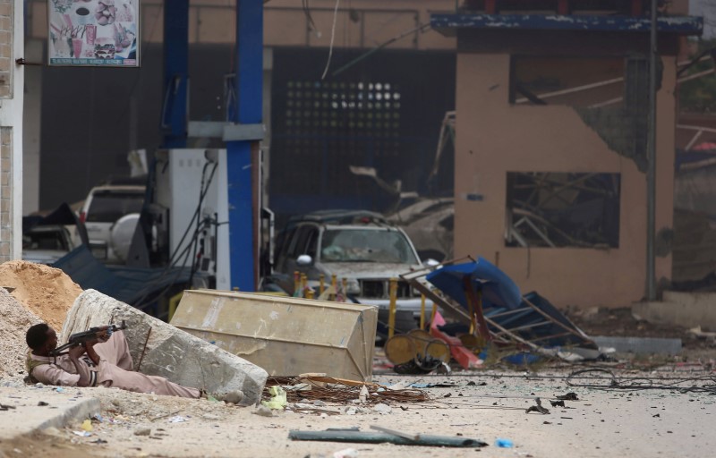 © Reuters. A Somali government soldier holds his position during gunfire after a suicide bomb attack outside Nasahablood hotel in Somalia's capital Mogadishu