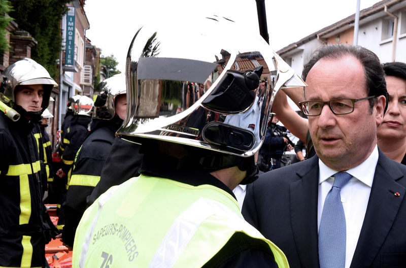 © Reuters. Presidente da França, François Hollande, conversando com bombeiro após ataque em Saint-Etienne-du-Rouvray