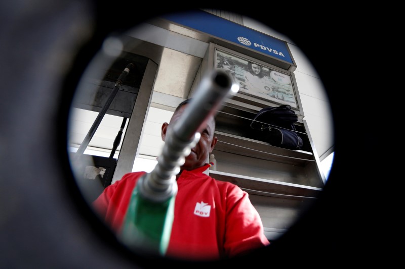 © Reuters. A man points a fuel nozzle at the camera for a photograph at a gas station belonging to Venezuelan state oil company PDVSA in Caracas