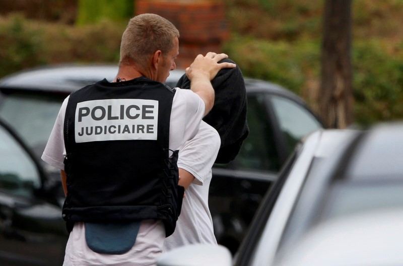 © Reuters. French judicial inverstigating police apprehends a man during a raid after a hostage-taking in the church in Saint-Etienne-du-Rouvray near Rouen in Normandy