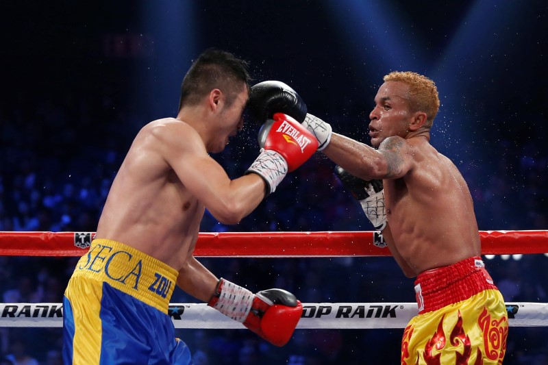 © Reuters. Amnat of Thailand punches Zou of China during their IBF world flyweight title fight in Macau