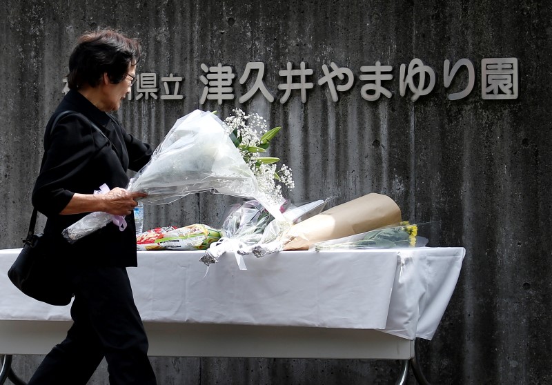 © Reuters. A woman offers flowers to mourn victims at the entrance of a facility for the disabled, where a deadly attack by a knife-wielding man took place, in Sagamihara, Kanagawa prefecture, Japan