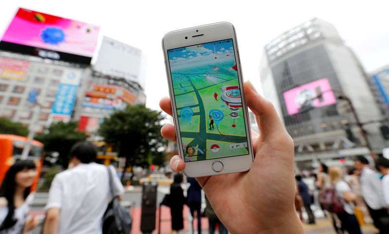 © Reuters. A man poses with his mobile phone displaying the augmented reality mobile game "Pokemon Go" by Nintendo in front of a busy crossing in Shibuya district in Tokyo