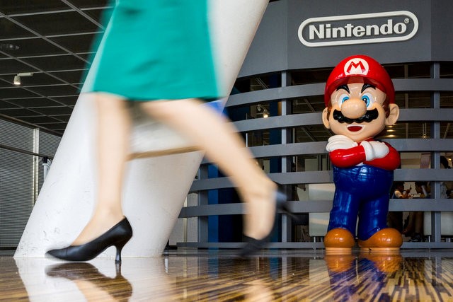 © Reuters. Woman walks past figure of "Mario" video game character at Nintendo centre in Tokyo