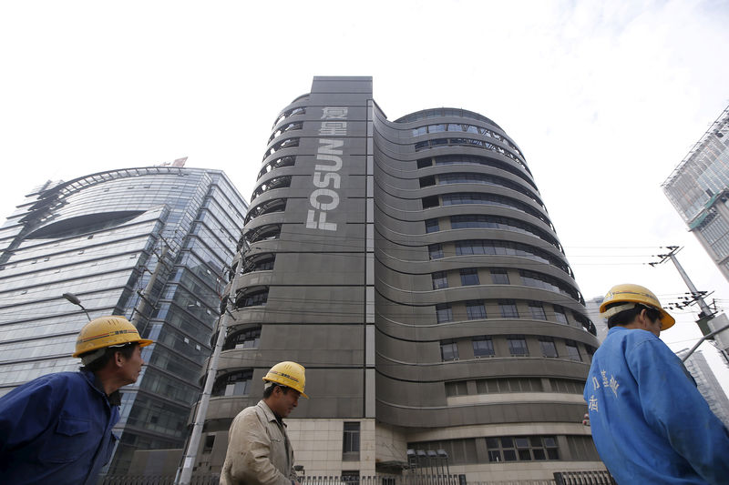 © Reuters. Construction workers walk past a building of the headquarters of Fosun International, in Shanghai