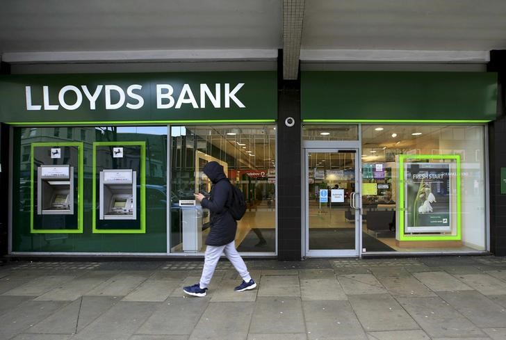 © Reuters. File photo of a man walking past a Lloyds Bank branch in London