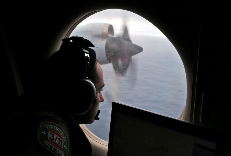 © Reuters. Flight officer Gharazeddine looks out of a RAAF AP-3C Orion as it flies over the southern Indian Ocean during the search for missing flight MH370