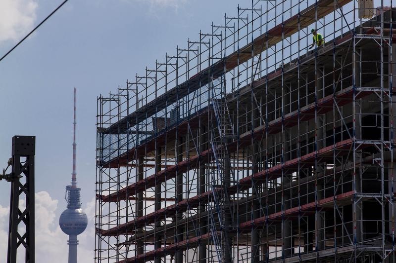 © Reuters. A worker is seen behind scaffoldings at a construction site near the Fernsehturm TV tower in Berlin