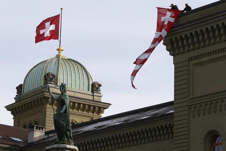 © Reuters. Workers hang up a Swiss flag on the Swiss parliament building in Bern