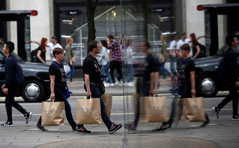 © Reuters. Shoppers are reflected in a window as they walk along Oxford Street in London