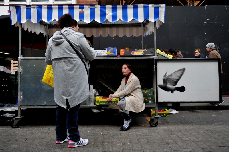 © Reuters. A woman arranges her stall as she chats to her friend at the Moore Street fruit and vegetable market in Dublin