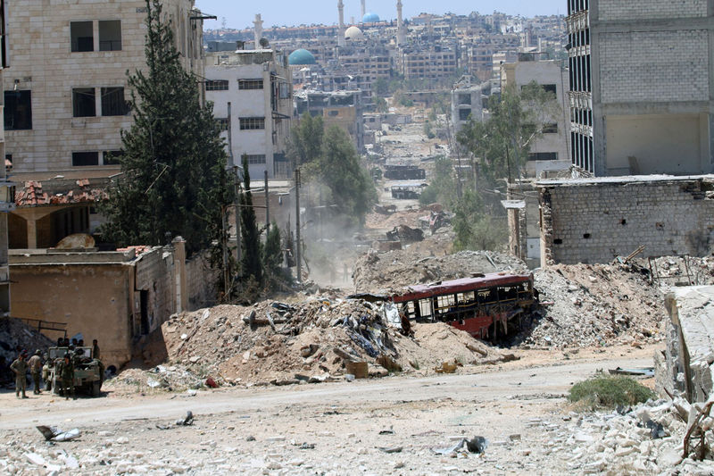 © Reuters. Forces loyal to Syria's President Bashar al-Assad stand near barricades after they advanced on the southern side of the Castello road in Aleppo