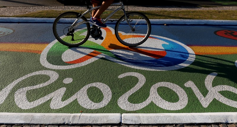 © Reuters. Woman rides her bicycle as she passes over a newly-painted bicyle lane ahead of the Rio 2016 Olympic games in Rio de Janeiro