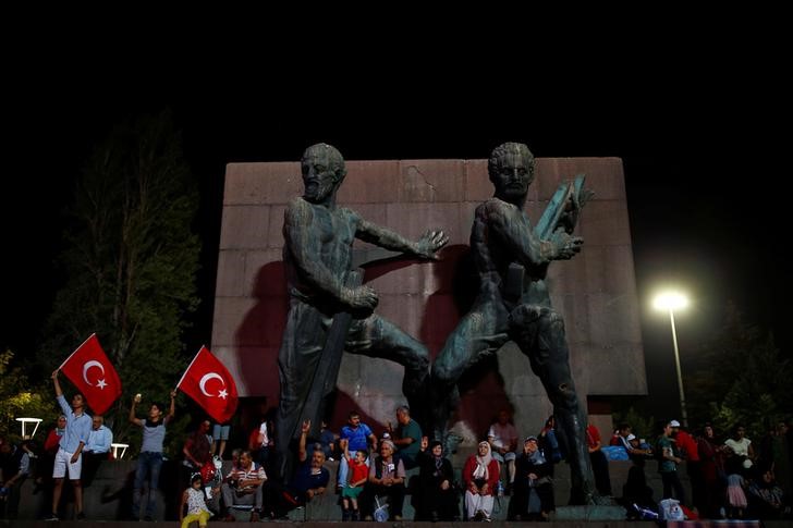 © Reuters. People sit in front of a statue as they gather in solidarity night after night since the July 15 coup attempt in central Ankara