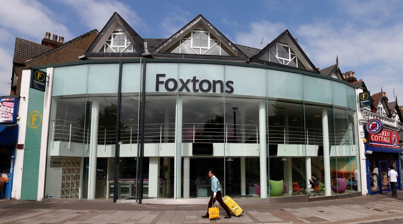 © Reuters. A man pulls a suitcase past a branch of Foxtons estate agent, in north London