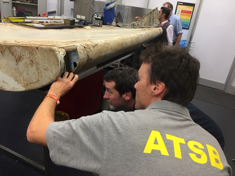 © Reuters. Australian and Malaysian officials examine aircraft debris at the Australian Transport Safety Bureau headquarters in Canberra, Australia, after it was found on Pemba Island, located near Tanzania, in late June and was transported to Australia