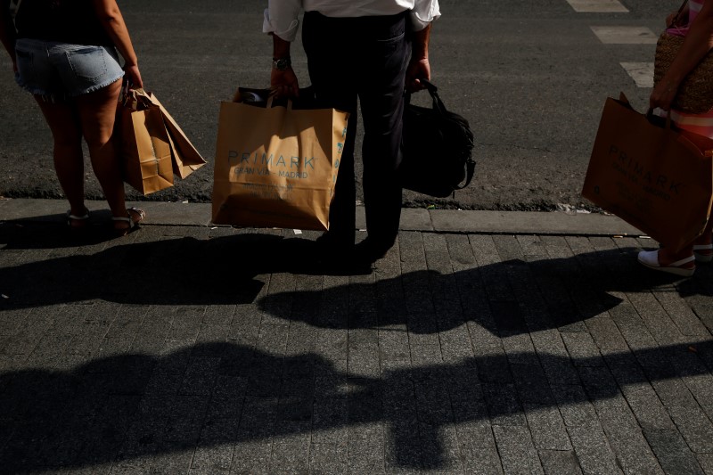 © Reuters. People hold shopping bags as they wait to cross Gran Via street in downtown Madrid