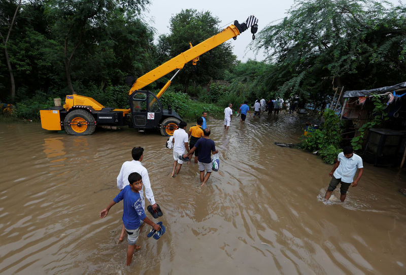 © Reuters. People wade through a waterlogged street next to a highway after heavy rains in Gurugram