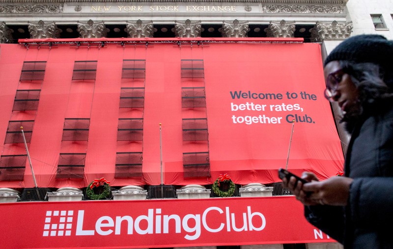 © Reuters. A woman looks at her phone as she passes by a Lending Club banner on the facade of the the New York Stock Exchange