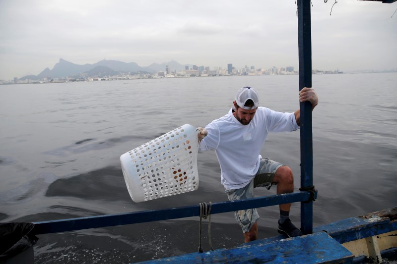 © Reuters. American sailor Brad Funk collects garbage during a small clean-up effort to remove rubbish from the notoriously dirty Guanabara Bay, ahead of the Rio 2016 Olympic Games