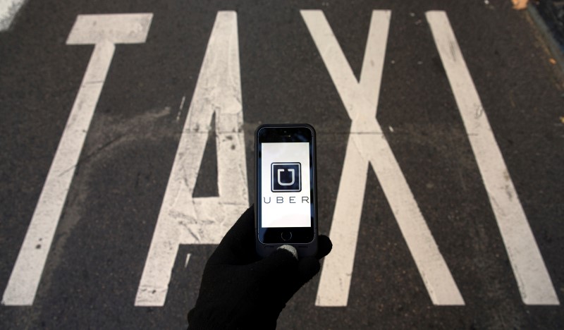 © Reuters. Photo illustration of logo of car-sharing service app Uber on a smartphone over a reserved lane for taxis in a street in Madrid