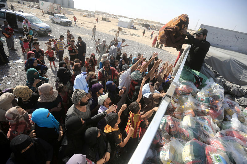 © Reuters. Displaced people, who fled from Al-Shirqat due to Islamic State violence, receive aid on the outskirts of Al-Shirqat, south of Mosul