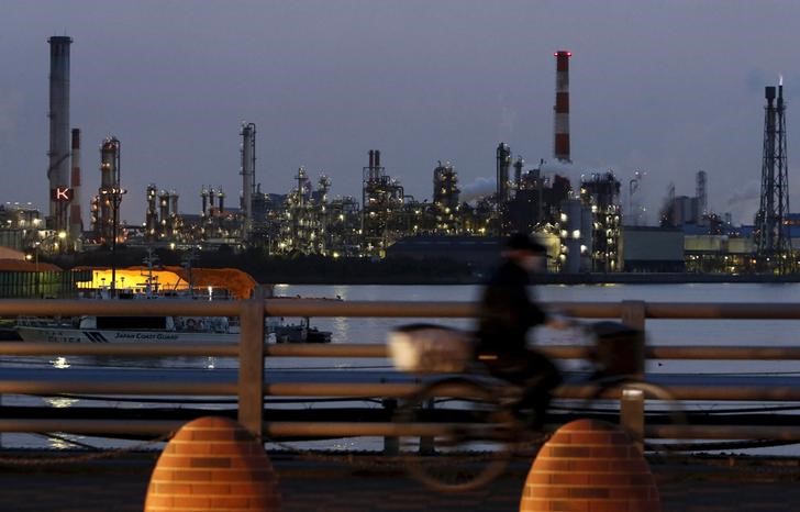 © Reuters. File photo of a man riding a bicycle past chimneys at factories at the Keihin industrial zone in Kawasaki