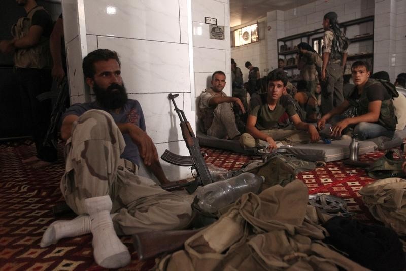 © Reuters. Rebel fighters rest near their weapons inside a safe house in the rebel held al-Rashideen neighbourhood, Western Aleppo province