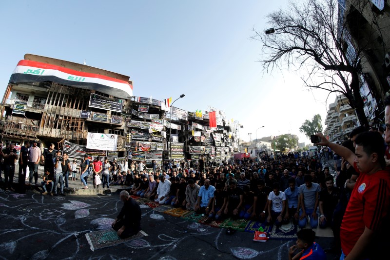 © Reuters. Sunni and Shi'ite Muslims attend prayers during Eid al-Fitr at the site of a suicide car bomb attack over the weekend at the shopping area of Karrada, in Baghdad