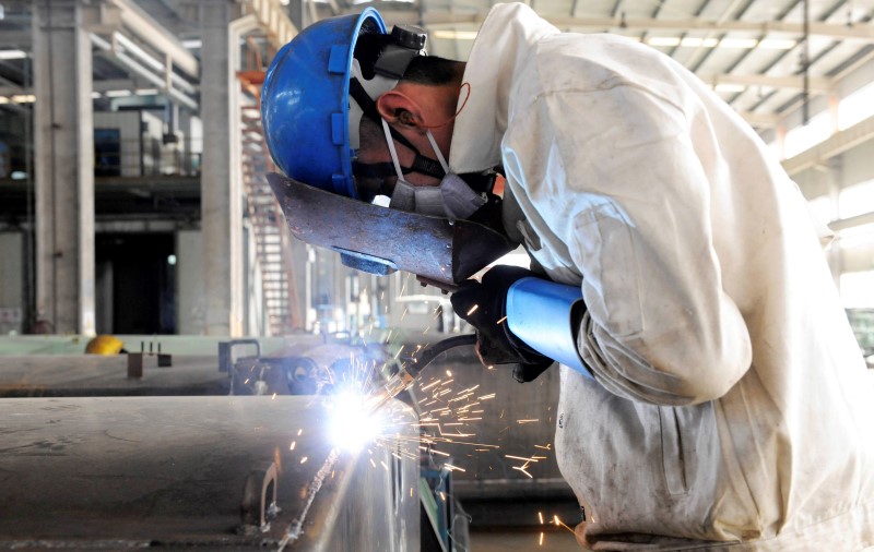 © Reuters. Employee welds the exterior of a vehicle along a production line at a factory in Qingdao