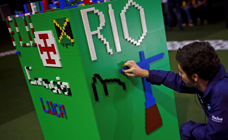 © Reuters. A man arranges LEGO bricks to build a Rio sign during a LEGO presentation of a massive model of the city including the Olympic sites at the Media Center in Rio de Janeiro