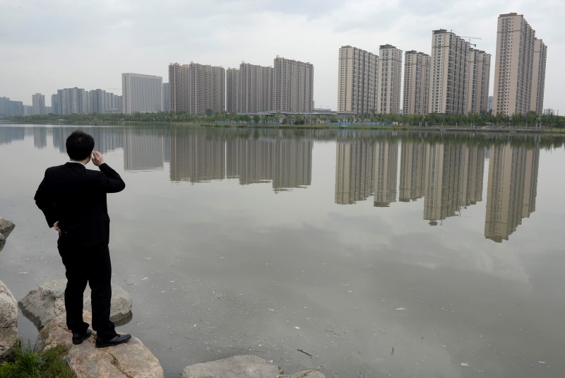 © Reuters. A man talks on his phone near a new residential compound in Taiyuan
