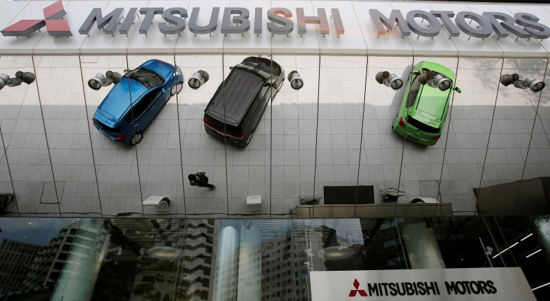© Reuters. Mitsubishi Motors Corp's vehicles and a passer-by reflected on an external wall at the company headquarters in Tokyo