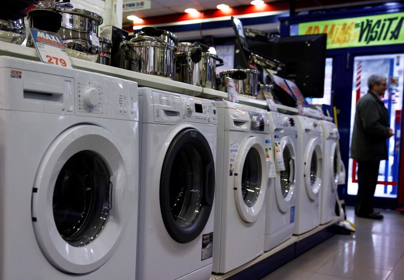 © Reuters. A man stands next to washing machines inside a household electrical appliance shop in Madrid