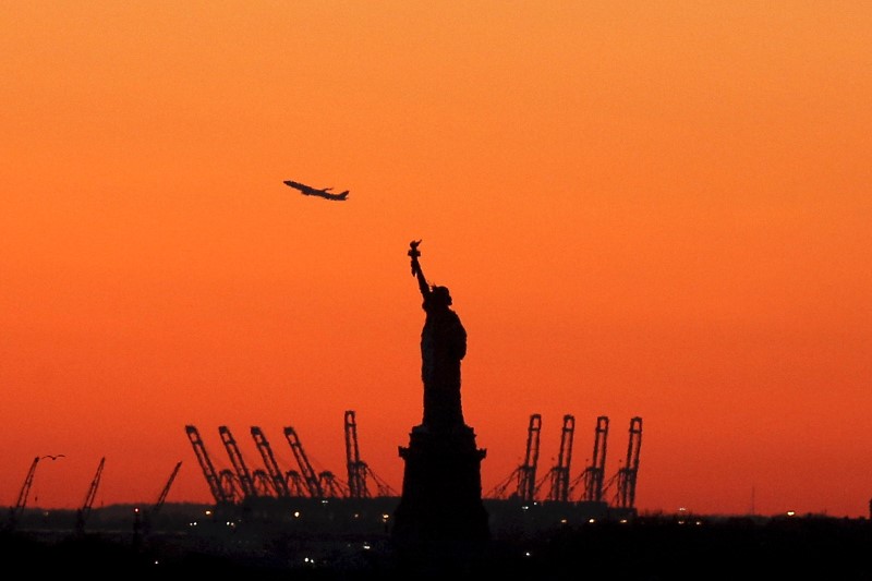 © Reuters. A plane is seen during take off behind the Statue of Liberty in New York's Harbor as seen from the Brooklyn borough of New York