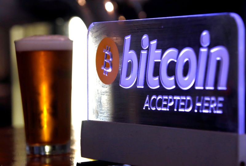 © Reuters. A beer sits next to a Bitcoin sign on display at a bar in central Sydney, Australia