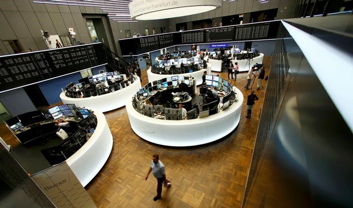 © Reuters. Traders work at their desks in front of the German share price index, DAX board, at the stock exchange in Frankfurt