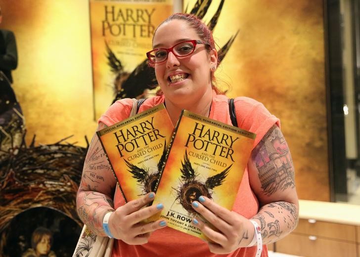 © Reuters. Uma mulher segura copias do livro Harry Porter e a Criança Amaldiçoada partes 1 e 2 em livraria em Londres