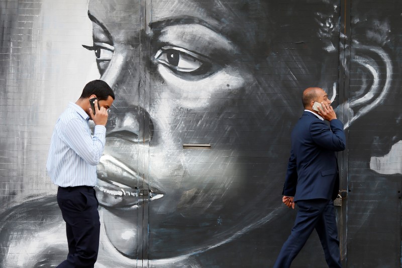 © Reuters. Men use their mobile phones next to a mural in London