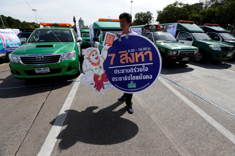 © Reuters. Thailand Election Commission's worker holds a banner during an event to promote voting at at the August 7 referendum on a new constitution in Bangkok