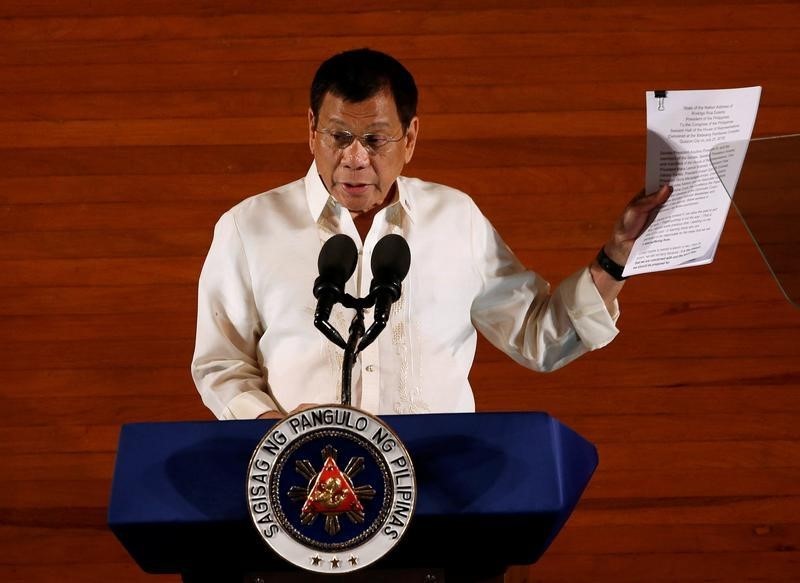 © Reuters. Philippine President Rodrigo Duterte holds up a copy of his speech as he speaks before the lawmakers during his first State of the Nation Address at the Philippine Congress in Quezon city, Metro Manila