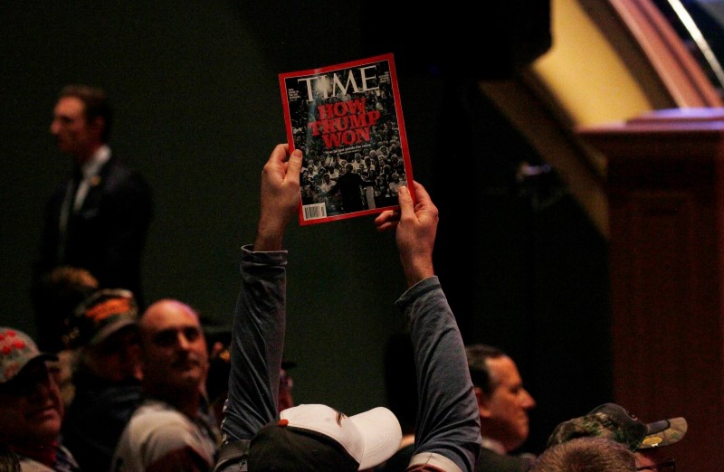 © Reuters. A supporter holds up a copy of Time Magazine with the cover headline "How Trump Won" during Trump's speech at a veteran's rally in Des Moines