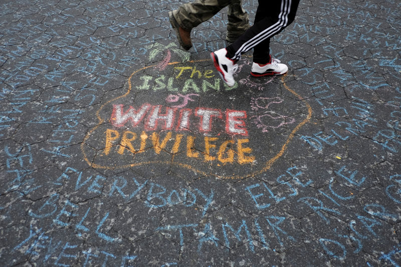 © Reuters. People walk over the names of people killed by police as they take part in a protest against the killing of Alton Sterling, Philando Castile and in support of Black Lives Matter during a march along Manhattan's streets in New York