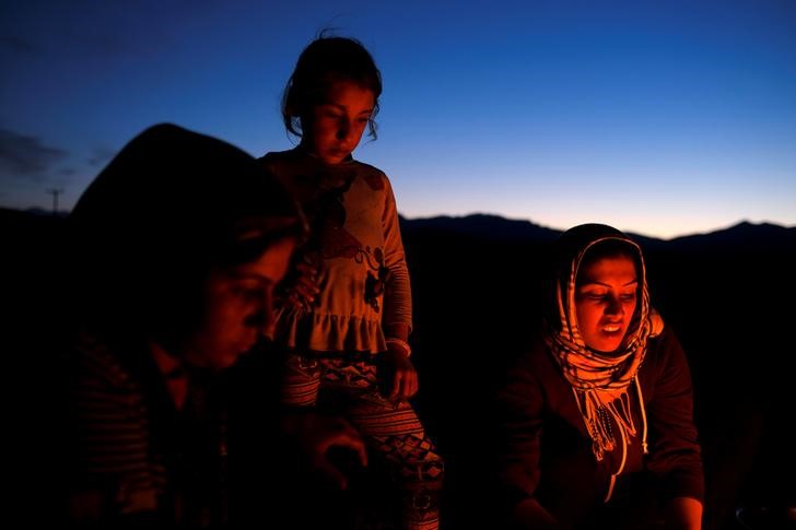 © Reuters. A girl watches as women prepare dinner at a makeshift camp for refugees and migrants at the Greek-Macedonian border near the village of Idomeni