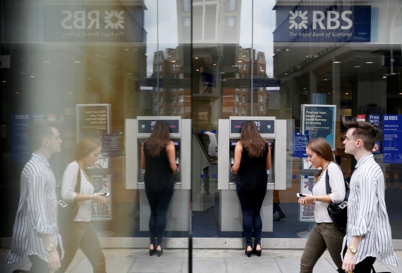 © Reuters. Pedestrians are reflected in the glass of an advertising board as they walk past a branch of The Royal Bank of Scotland in central London