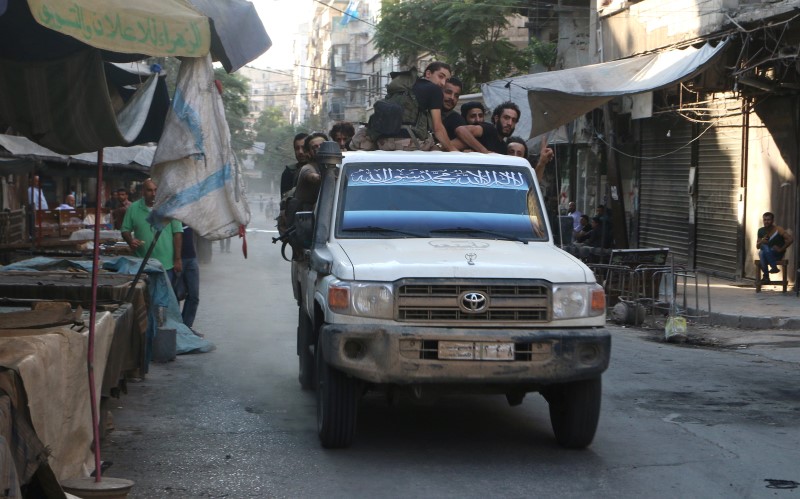 © Reuters. Free Syrian Army fighters ride on a vehicle past empty merchandise stalls in Aleppo's rebel-controlled Bustan al-Qasr neighbourhood due to a siege by Syrian pro-government forces that cut the supply lines into opposition-held areas of the city